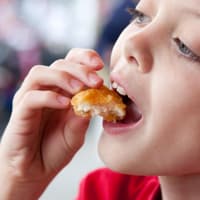 Junge isst Chicken Nuggets.