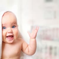 Lachendes Baby unter Handtuch.