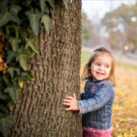 Fröhliches Kind läuft um Efeu-berankten Baum