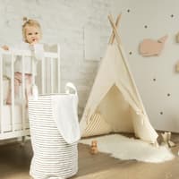 Ein kleines Mädchen steht in ihrem Kinderbett im Kinderzimmer.