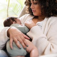 Junge Mutter stillt ihr Baby in einer ihrer liebsten Stillpositionen.