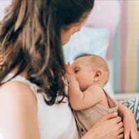 Eine Frau stillt im Sitzen ihr Baby.