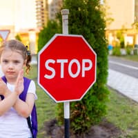 Grenzen ziehen: Kleines Schulmädchen sagt Nein an einem Stopp-Schild