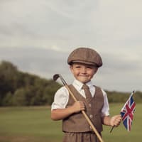 Englischer kleiner Junge in Vintage-Kleidung hält eine britische Flagge in der Hand