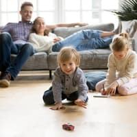 Kinder spielen, Eltern sitzen entspannt auf dem Sofa.