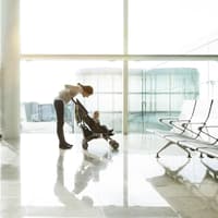 Mama mit Reisebuggy am Flughafen