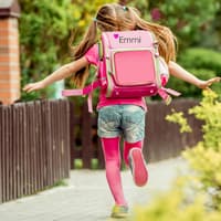 Mädchen mit einem bestickten Schulranzen läuft den Gehweg entlang.