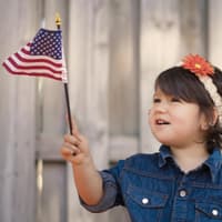 Kleines Mädchen hält eine Amerika-Flagge in der Hand. 