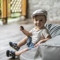 Ein kleiner Junge sitzt auf einem Sitzsack und schaut in die Kamera.