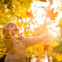 Ein Mädchen spielt mit Herbstblättern