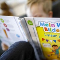 Ein kleiner Junge liest in einem Tiptoi-Buch zum Thema "Unser Zuhause".