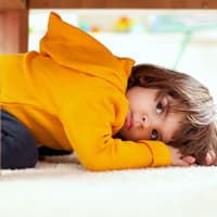 Kleiner Kita-Junge versteckt sich unter einem Tisch.