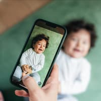 Ein Baby, das mit einem Handy fotografiert wird.