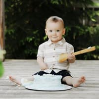 Ein kleiner Junge, der frech in die Kamera grinst und von einer Torte nascht.