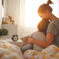 Mutter weckt ihre Tochter morgens im Bett.