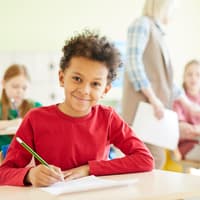 Schüler sitzt lächelnd im Klassenraum.