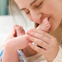 Mama küsst die Füßchen ihres Babys.