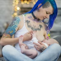 Tätowierte Frau stillt ihr Baby.