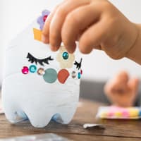 Kinderhand beklebt abgeschnittene PET-Flasche als Laterne.