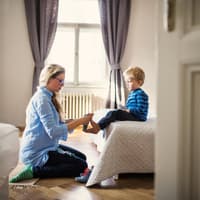 Mutter zieht ihrem Sohn die Socken an.