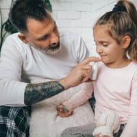 Ein Vater gibt seiner Tochter Nasenspray. 