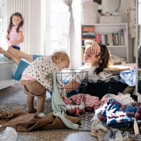 Gestresste Mutter mit zwei Kleinkindern zu Hause.