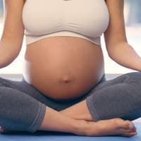 Nahaufnahme von schwangerer Frau beim Yoga.