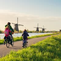 Holländische Familie fährt Fahrrad entlang von niederländischen Windmühlen. 