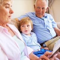 Oma und Opa lesen mit dem Enkel ein Buch. 