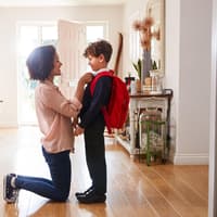 Mutter verabschiedet ihren Sohn vor der Schule.
