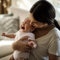 Mama hält zitterndes Baby im Arm.