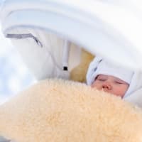 Baby schläft im Winter draußen im Kinderwagen.