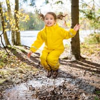 Kind spielt draußen und springt in Pfütze