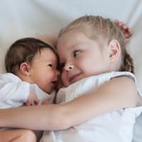 Mädchen hält Baby im Arm.