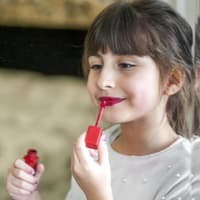 Ein kleines Mädchen, das sich mit Lipgloss schminkt