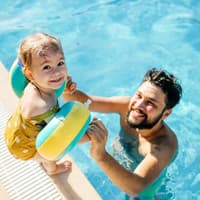 Kleinkind mit Schwimmflügeln und Papa.