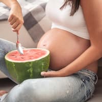 Schwangere löffelt Wassermelone.