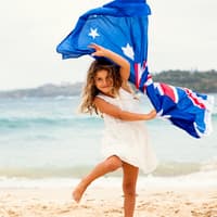 Ein Mädchen mit australischer Flagge am Strand. 