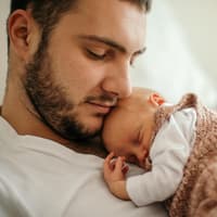 Kleines Baby schläft auf der Brust des Vaters.