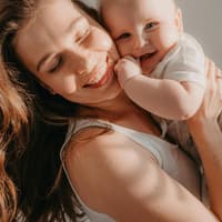 Glückliche Mutter mit süßem Baby auf dem Arm.
