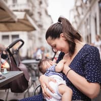Eine Mutter stillt ihr Baby draußen in einem Café.