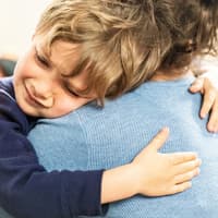 Ein kleiner Junge liegt weinend in den Armen seiner Mutter. 