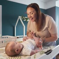 Eine Mutter wechselt ihrem Baby auf einer Wickelkommode die Windel. 