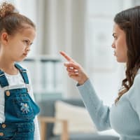 Mutter schimpft mit erhobenem Zeigefinder mit ihrer Tochter.