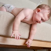 Baby beugt sich über den Bettrand.