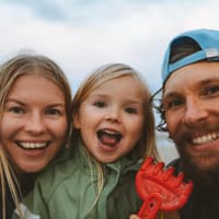 Mama, Papa und Kind lachen in die Kamera.