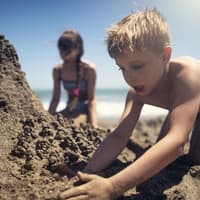 Kinder buddeln am Strand.