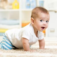 Baby krabbelt auf dem Teppich.