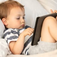 Kleiner Junge sitzt vor einem Tablet.