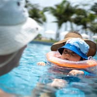 Baby mit Schwimmring um den Hals im Pool.